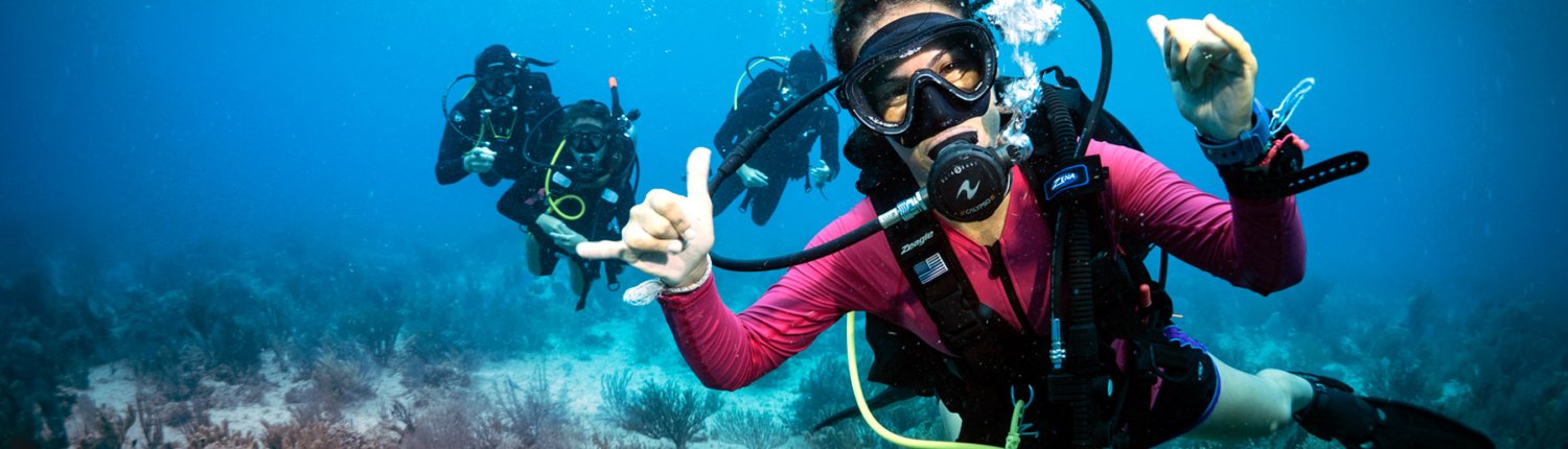 A smiling diver giving a shaka sign underwater