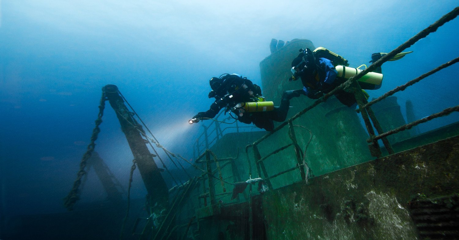 Divers with lights on a wreck